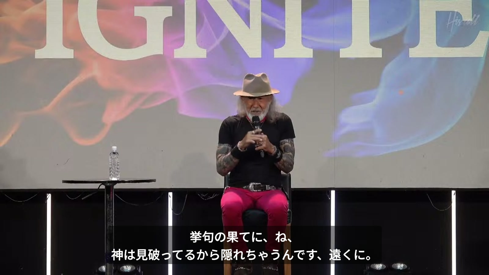 椅子に座り、マイクを持って語るアーサーホーランド