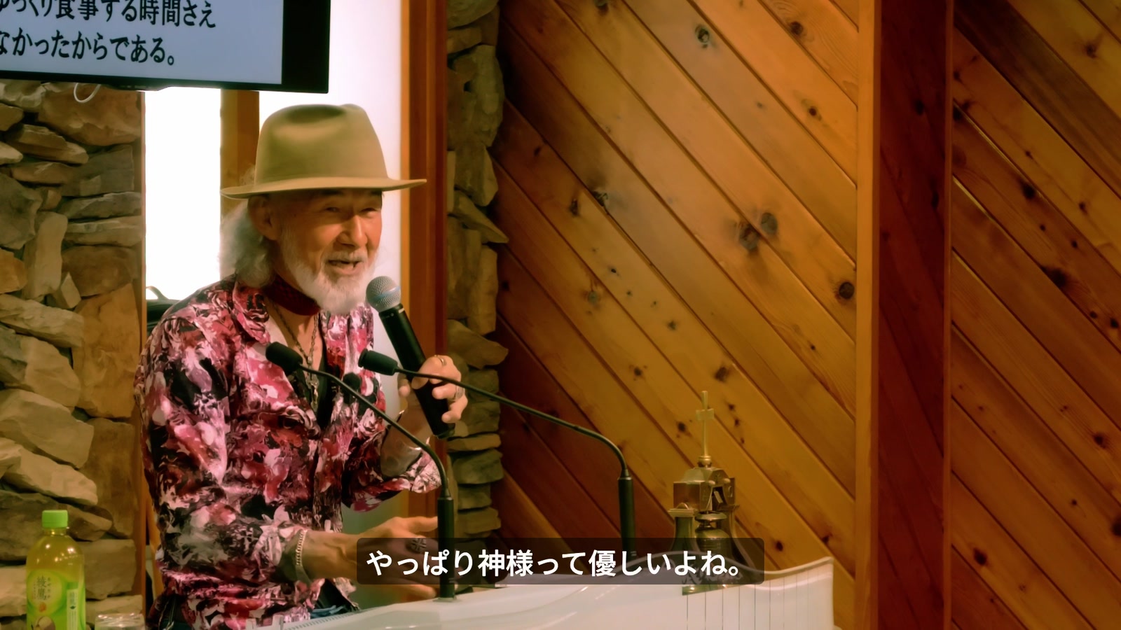 笑顔で「やっぱり神様って優しいよね」と語るアーサー・ホーランド。背後のモニターにはマルコ6章31節が映る