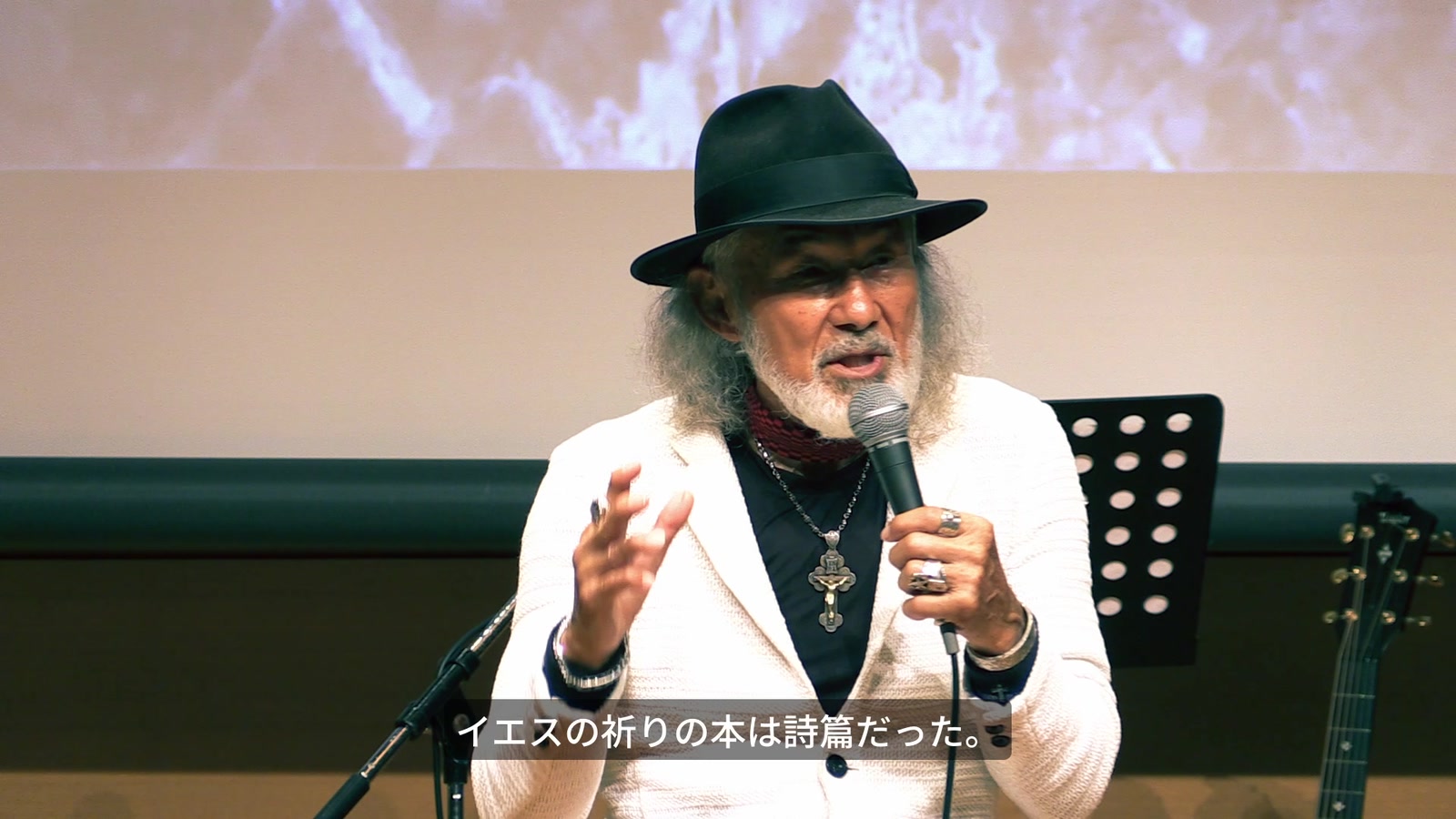会場でマイクを持ち、正面を向いて語るアーサー・ホーランズ