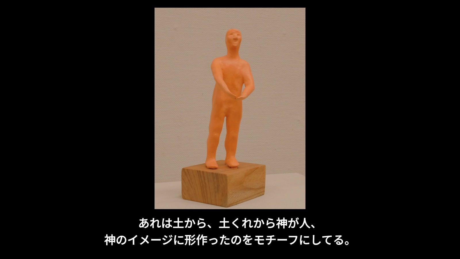 土くれから人を形作る姿を表したオレンジ色の造形作品
